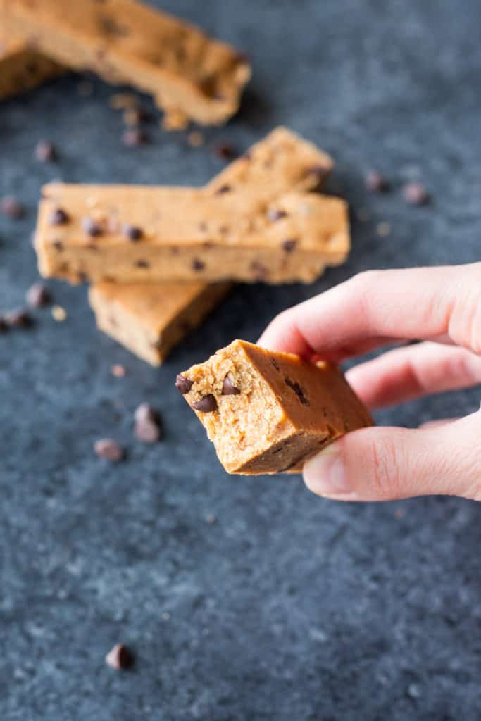 A stack of Almond Butter Cookie Dough Protein Bars with a hand holding one