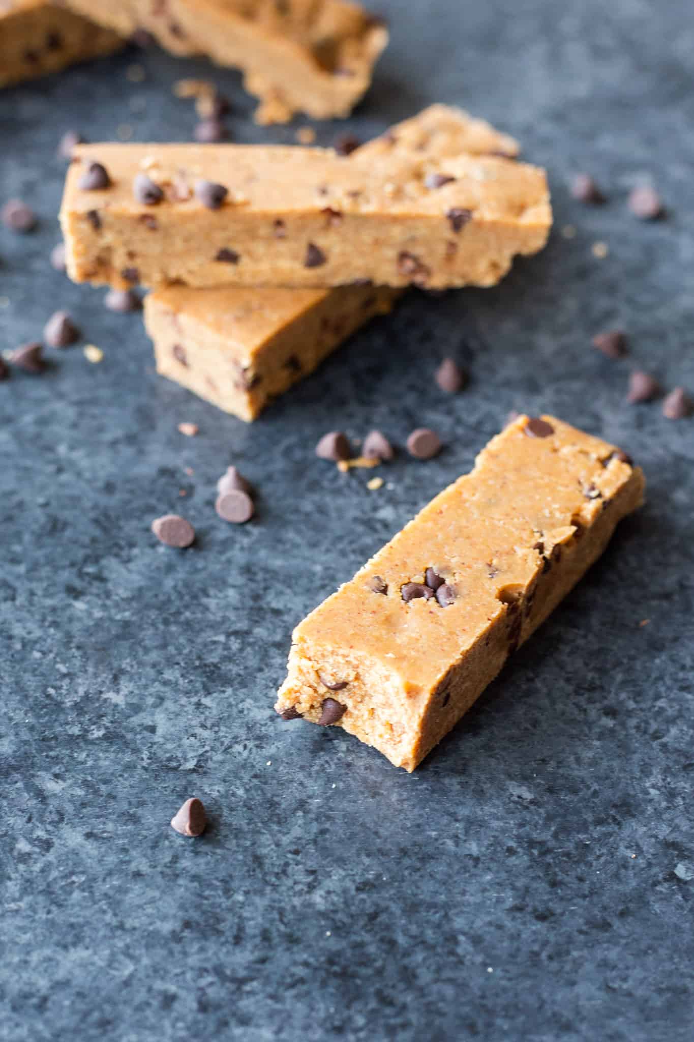 a stack of Almond Butter Cookie Dough Protein Bars with a bar in the front with a bite taken out of it