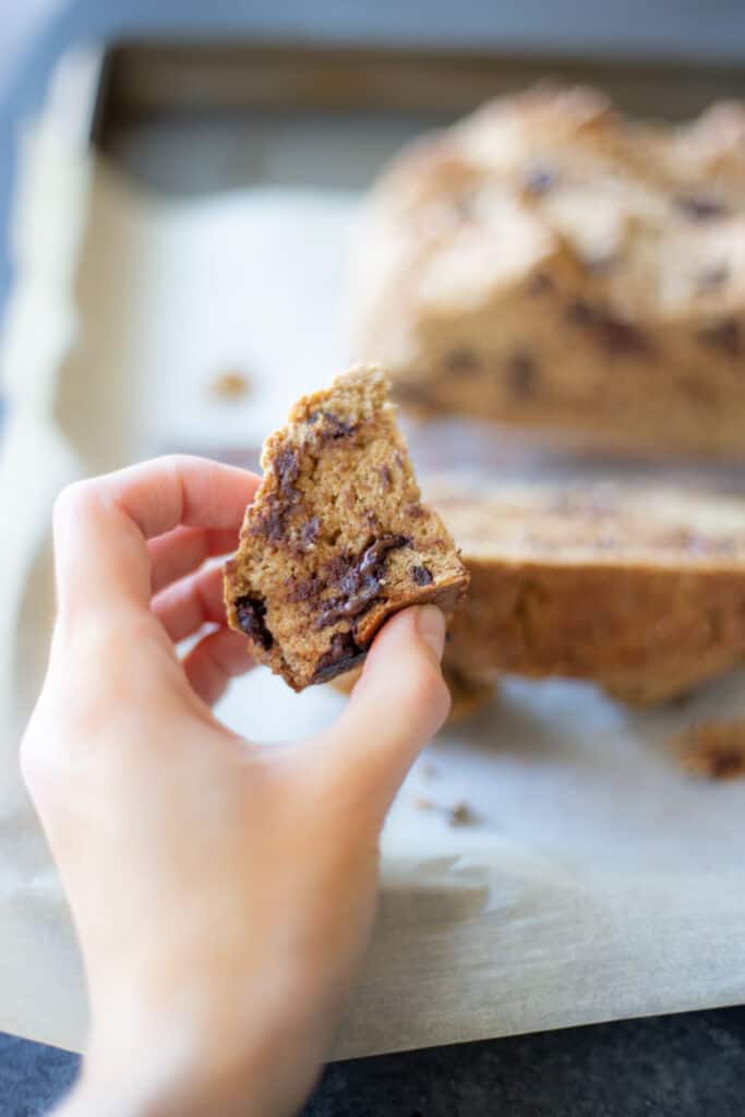 a hand holding up a piece of the stout chocolate chip soda bread