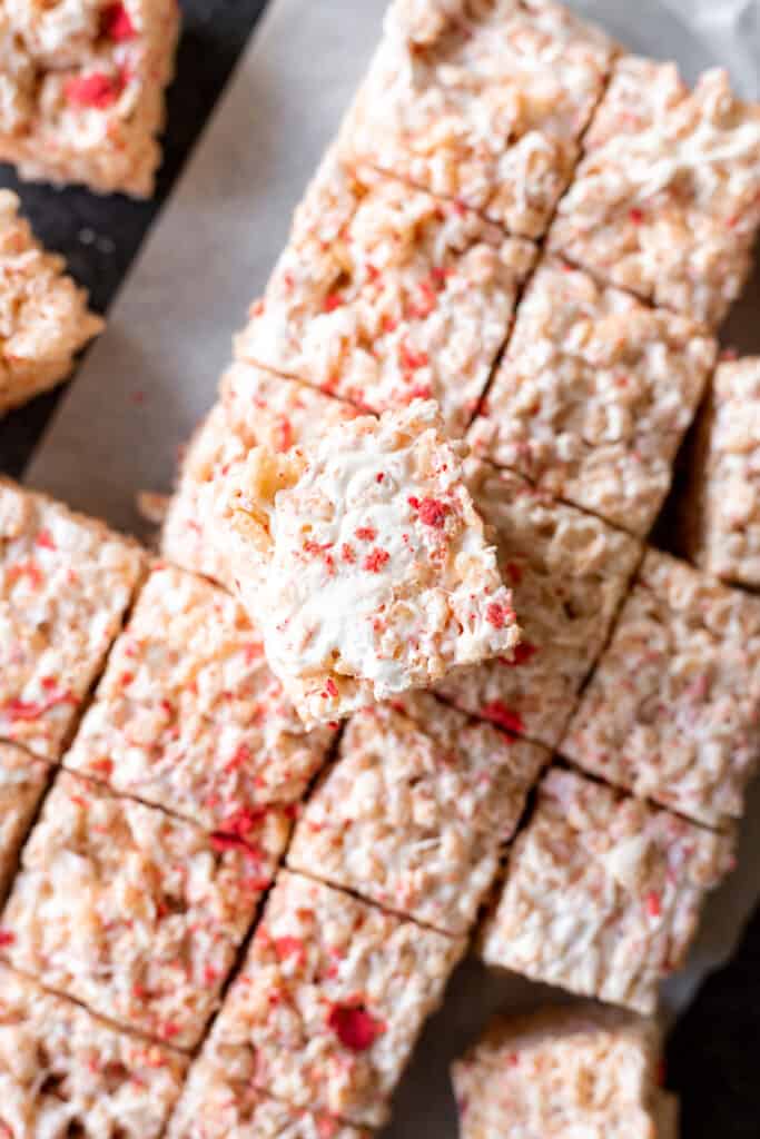 a strawberries and cream crispy rice treat on a pile of strawberries and cream crispy rice treats