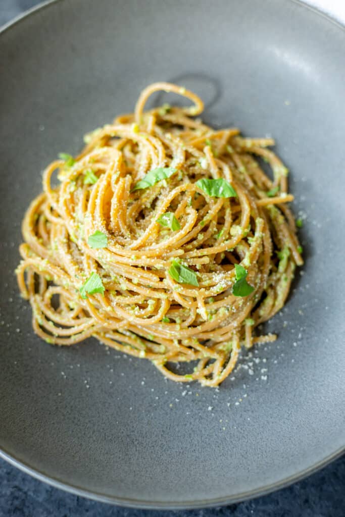 vegan garlic scape pesto on pasta in a dark grey bowl