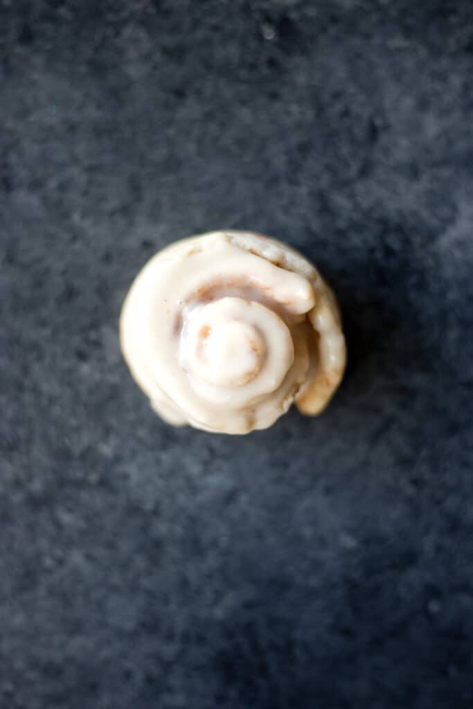 a top-down view of a vegan single serving cinnamon roll on a dark background
