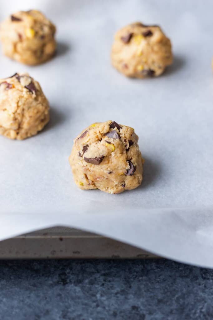 unbaked date pistachio chocolate chunk cookies on a parchment-lined baking sheet