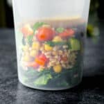 farro grain bowl in a meal prep container with the dressing on top