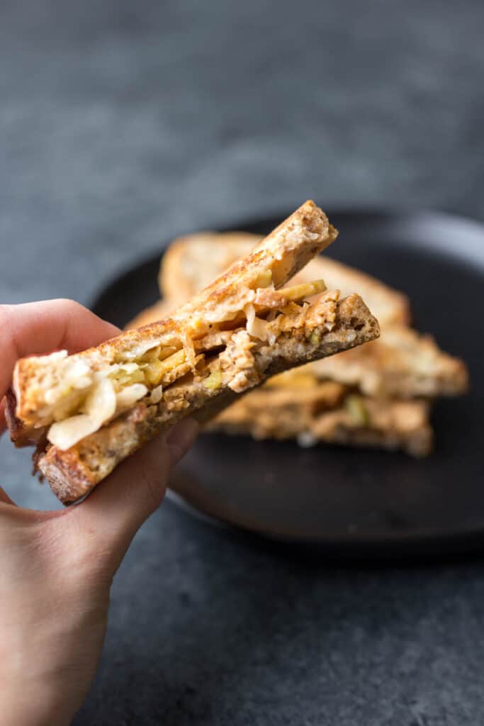 a hand holding a half of a vegan reuben sandwich on rye bread