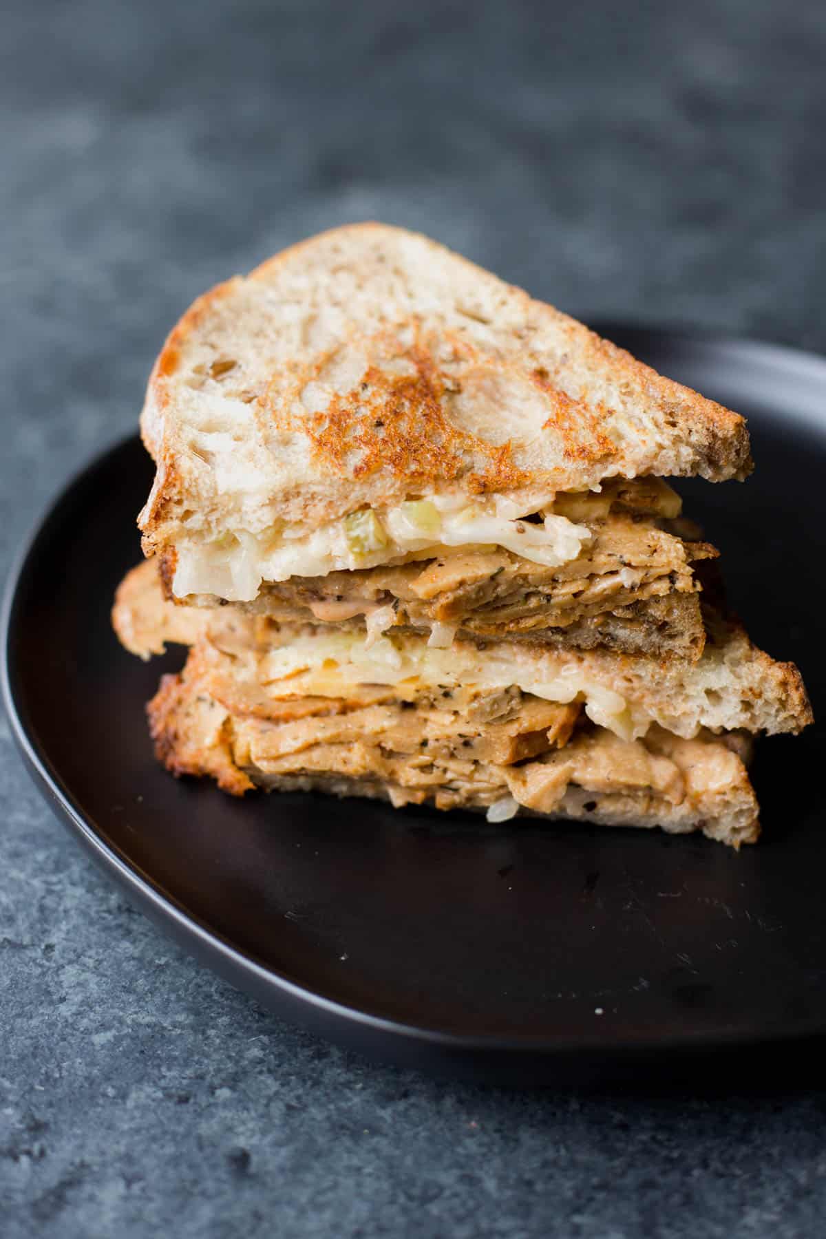 a sliced vegan reuben sandwich on a black plate