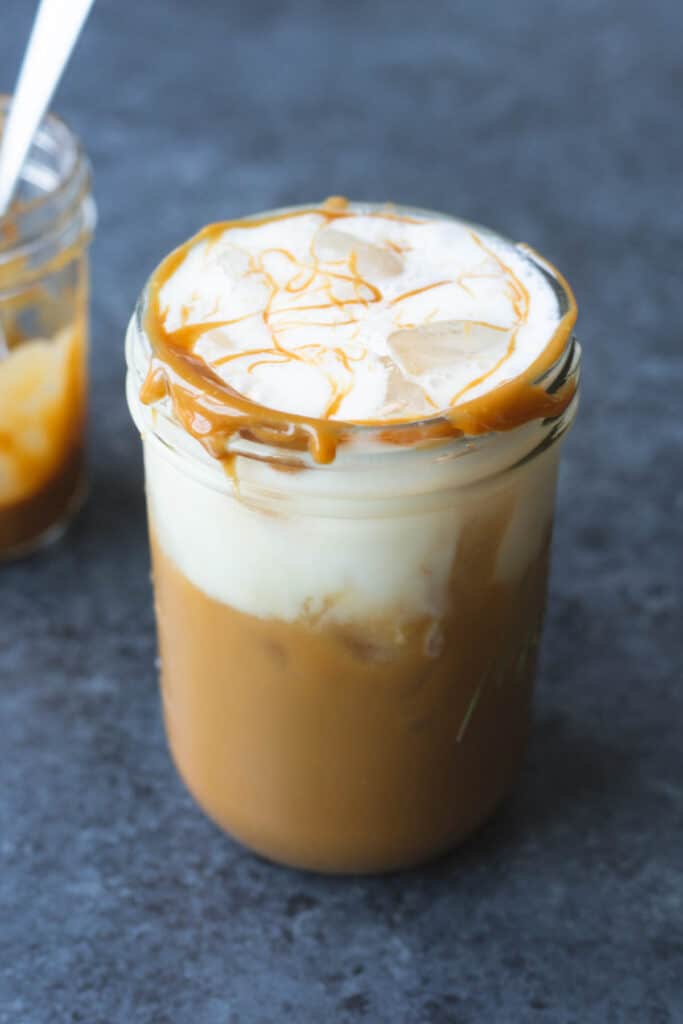 a cookie butter iced coffee with vanilla oatmilk cold foam in a mason jar