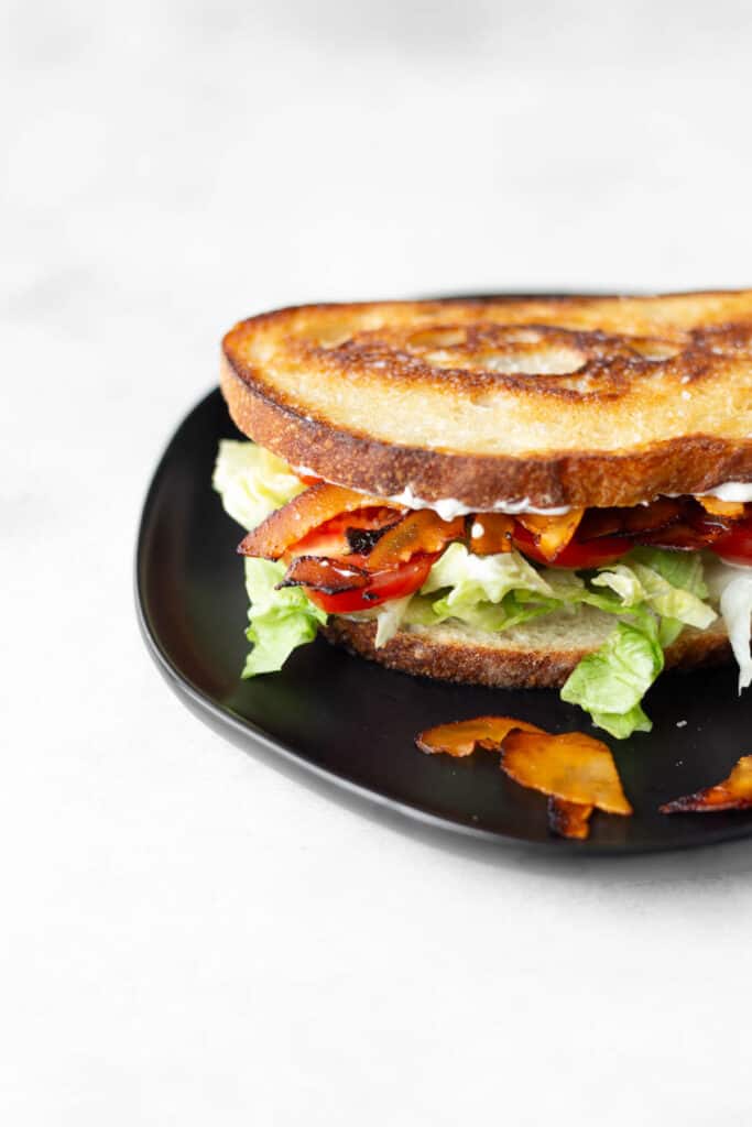 a vegan blt made with coconut bacon on a black plate