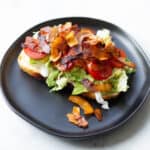 a topless vegan blt made with coconut bacon on a black plate