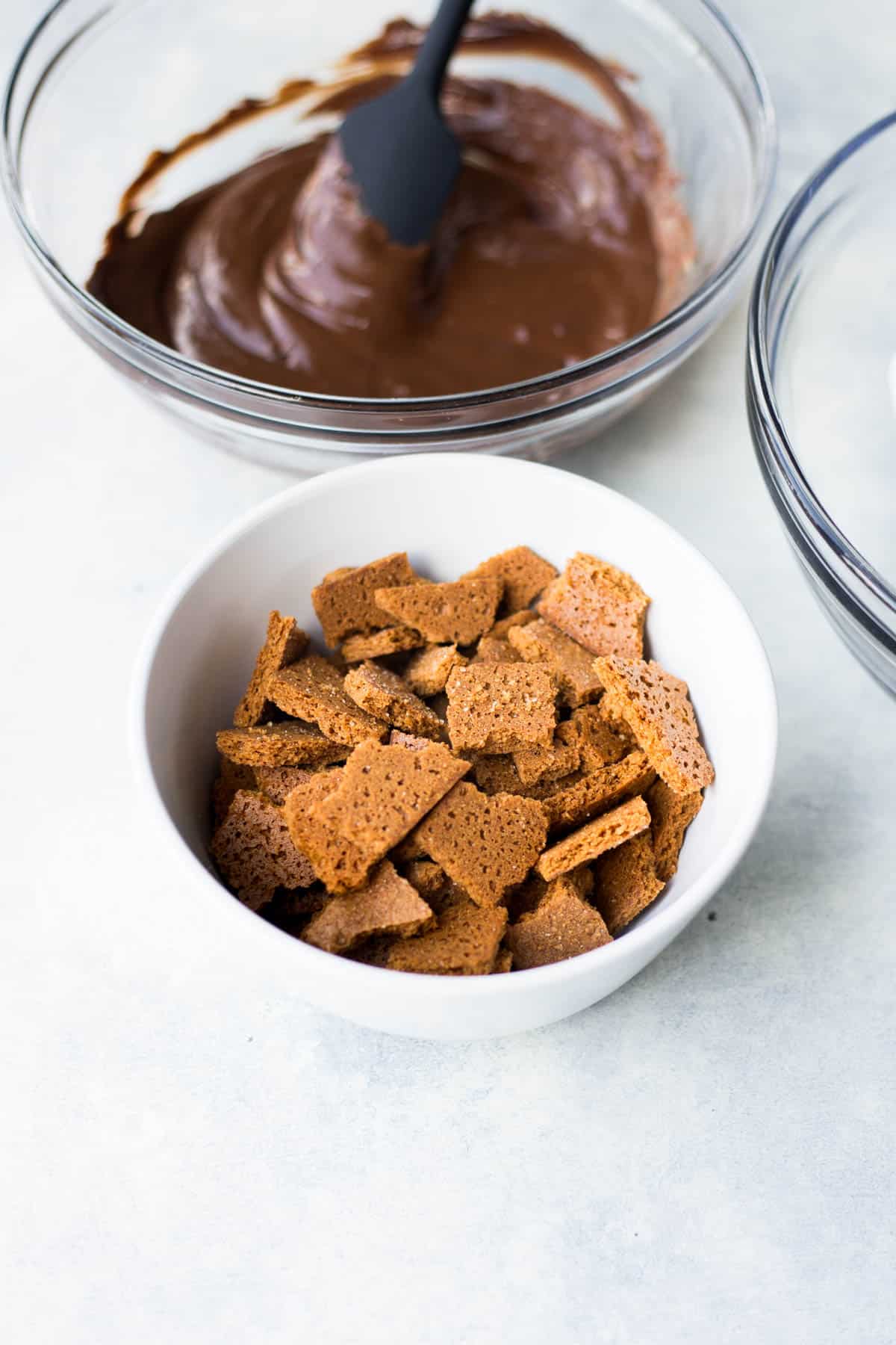 a bowl of chunks of graham crackers with a bowl of melted chocolate in the background