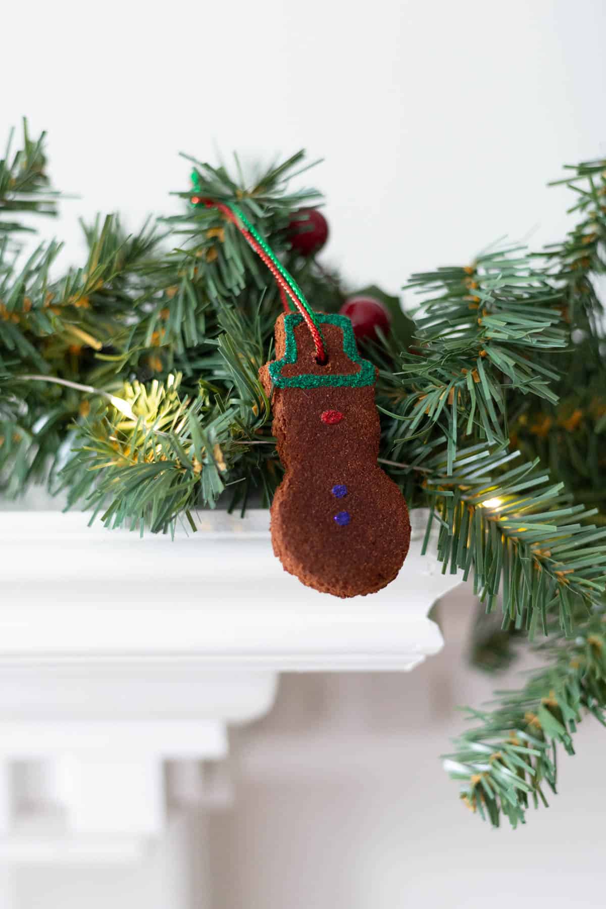 a snowman cinnamon ornament hanging on garland