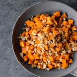 a bowl of granola-topped vegan maple roasted sweet potatoes