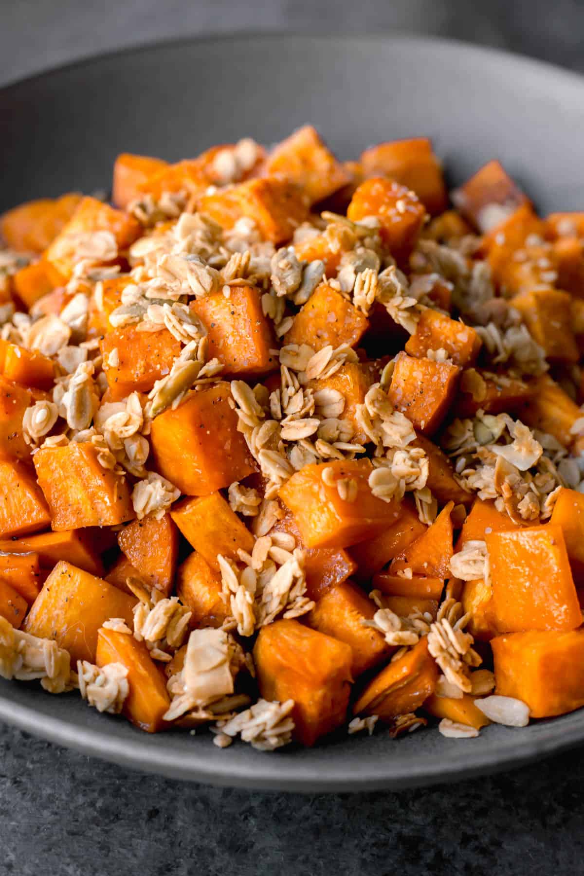 a close-up photo of a bowl of granola-topped vegan maple roasted sweet potatoes