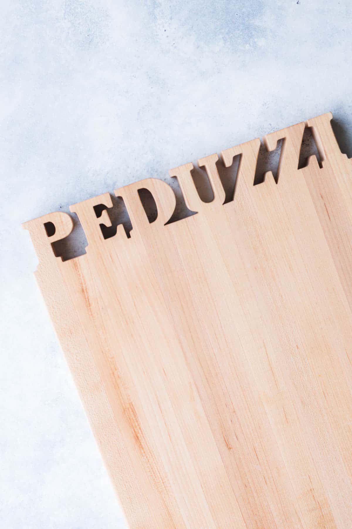 cutting board with the word "Peduzzi" lazer cut from it