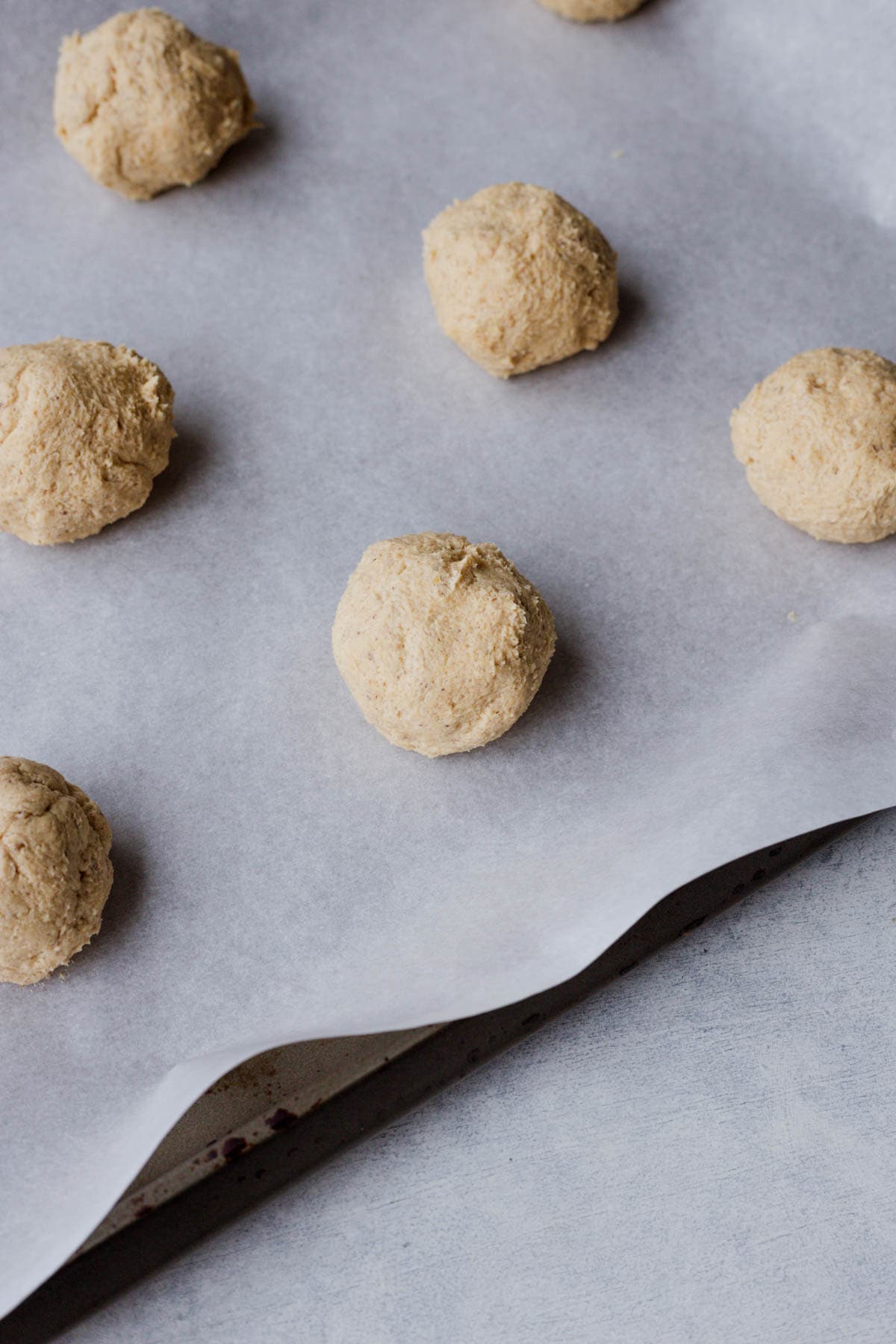 vegan chocolate peanut butter cookie dough balls on a parchment-lined baking sheet