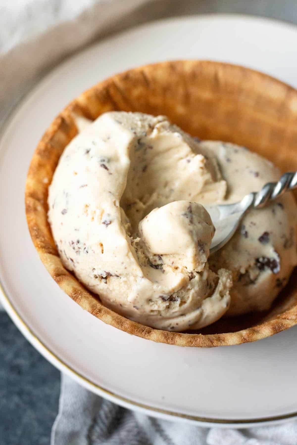 a spoon scooping chocolate peanut butter ice cream in a waffle bowl